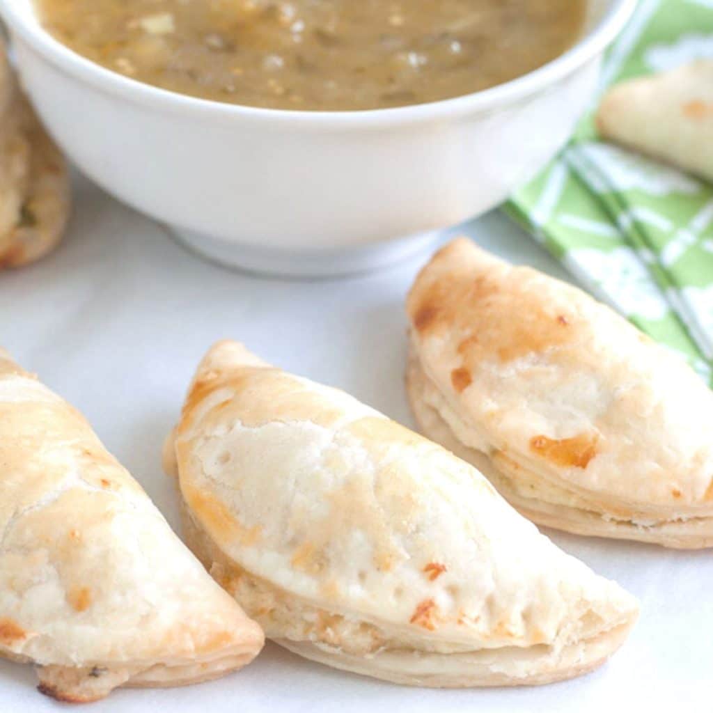 Empanadas with bowl of green salsa.