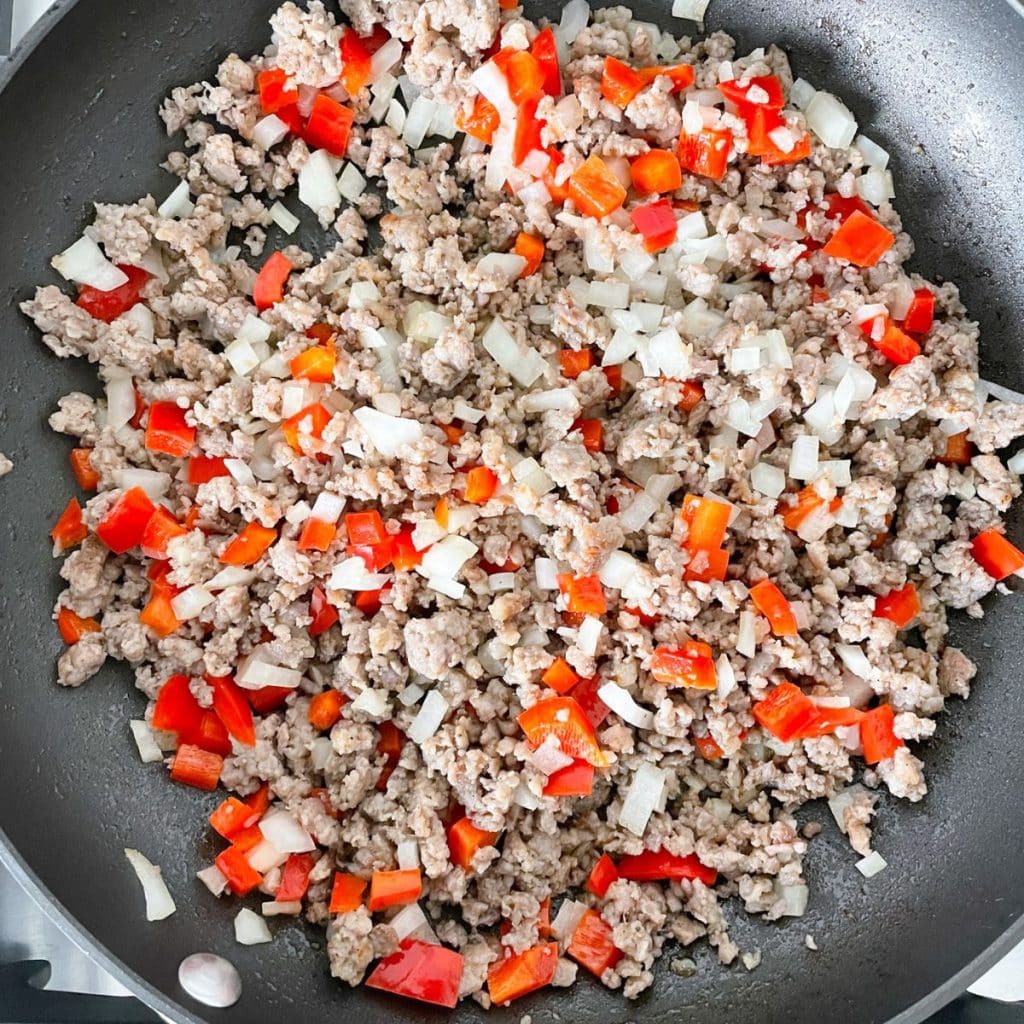 Pan with crumbled sausage, red pepper, and onion. 