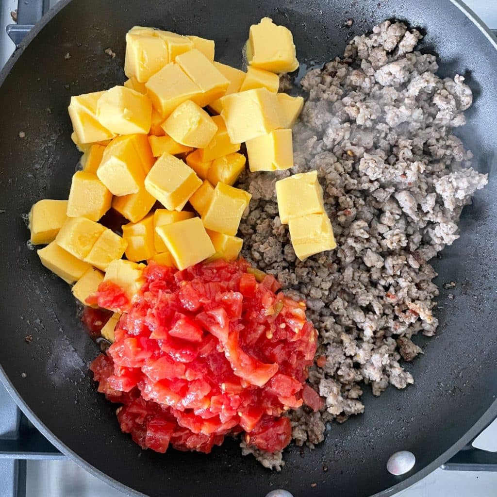 Skillet with sausage, cubed Velveeta, and diced tomatoes. 