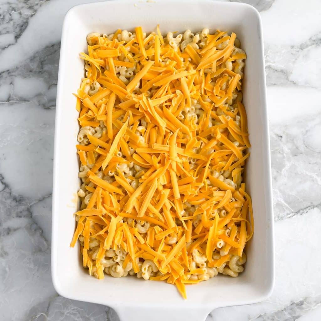 Casserole dish with mac and cheese topped with shredded cheese.