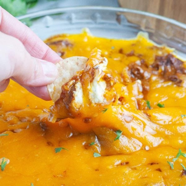 Hand holding chip with cheese dip.