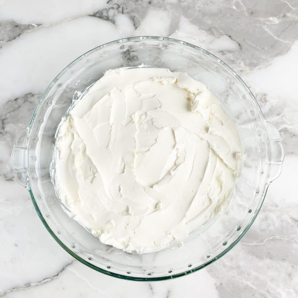 Pie dish with cream cheese spread on the bottom.