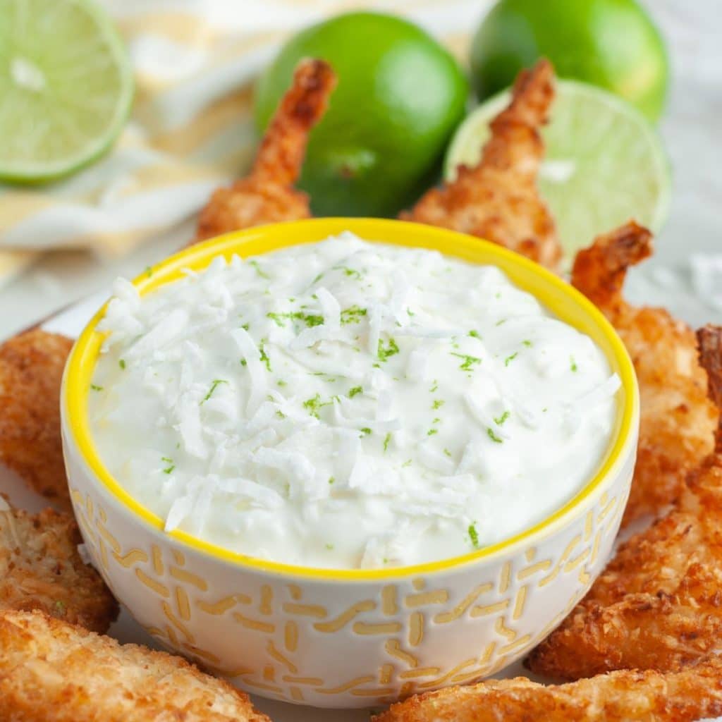 Bowl of white sauce and coconut shrimp.