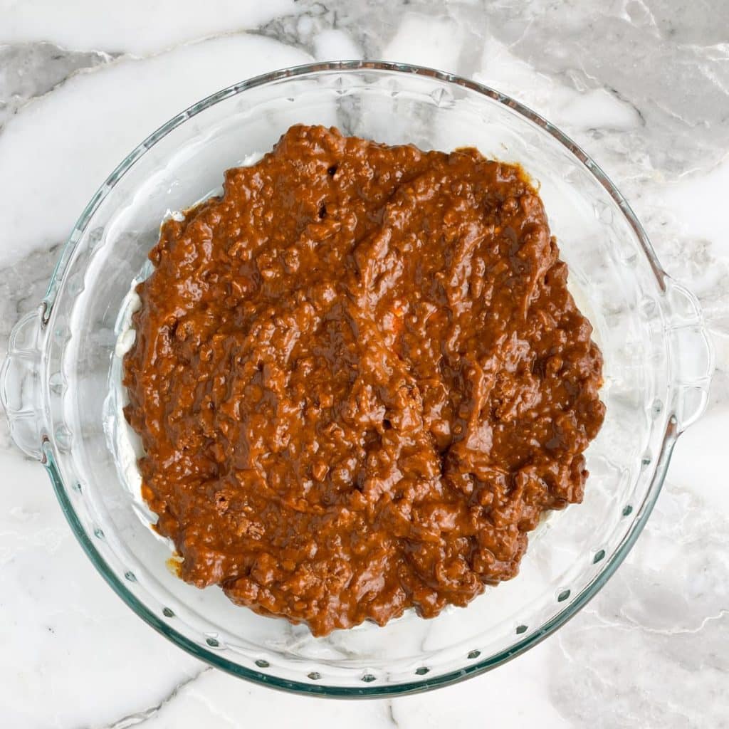 Chili spread over cream cheese in a pie plate.