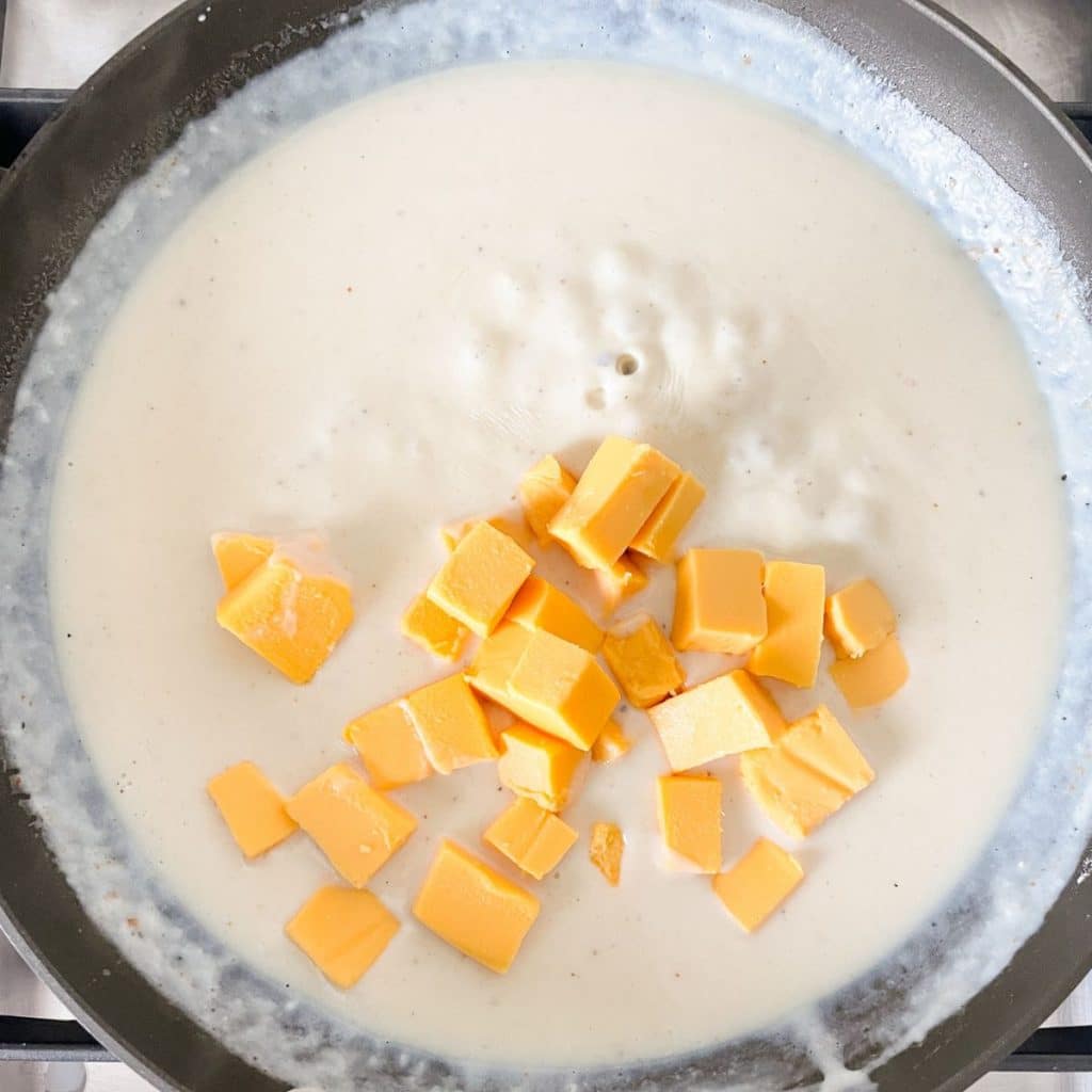 Skillet with cream sauce and cubed Velveeta.