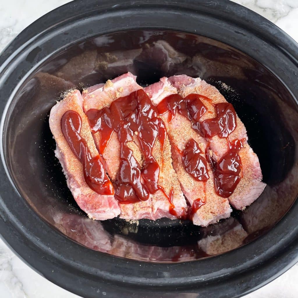 Slow cooker with ribs and BBQ sauce. 