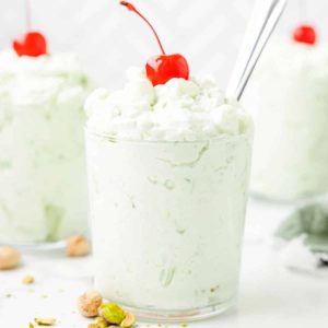 Glasses of watergate salad topped with a cherry.