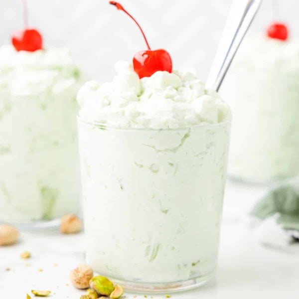 Glasses of watergate salad topped with a cherry.