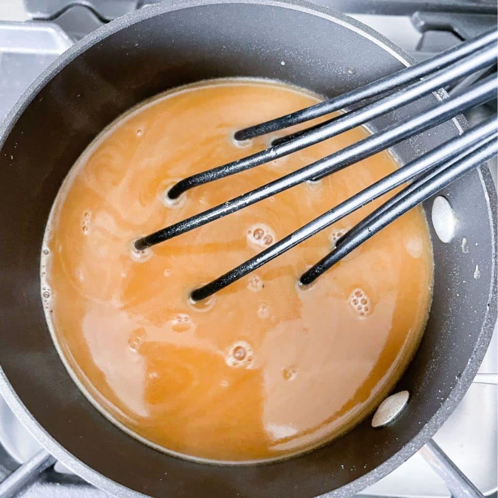 Pot with brown gravy and whisk. 