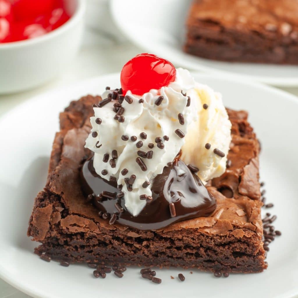 Brownie topped with ice cream, fudge, and cherry.