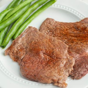 Cooked steak on a plate with green beans.