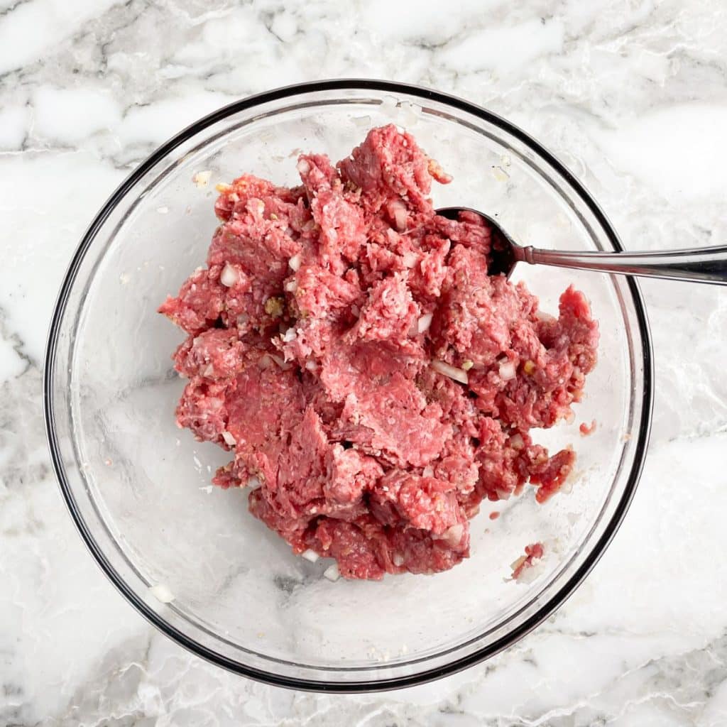 Bowl with ground beef and seasoning. 