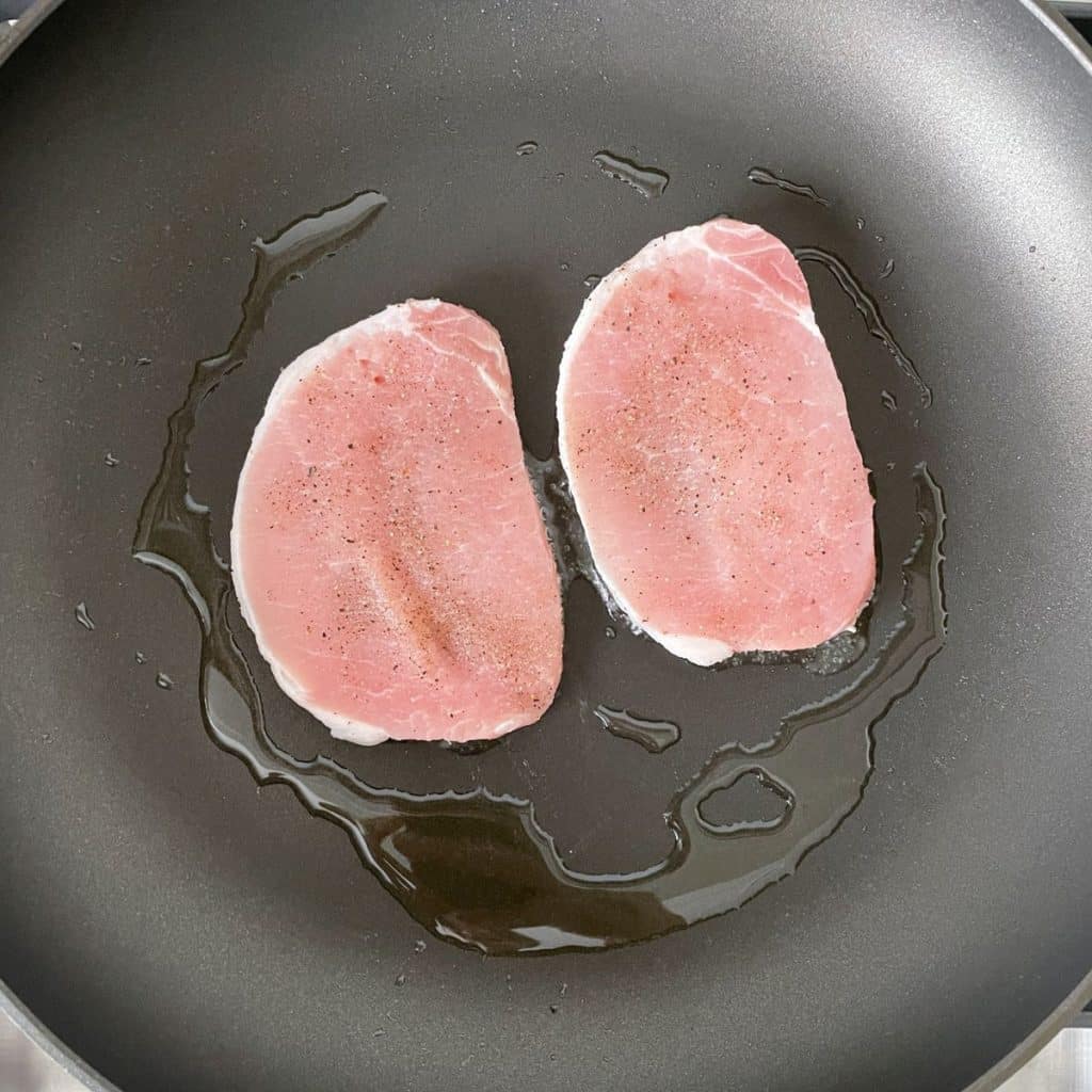 Pork chops in a skillet.