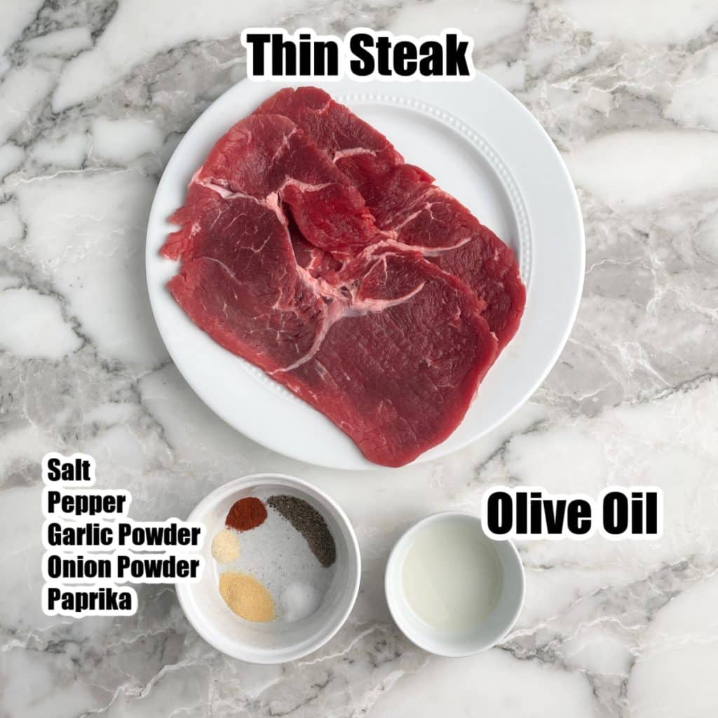 Plate with thin steak, bowl with spices, and bowl with olive oil. 
