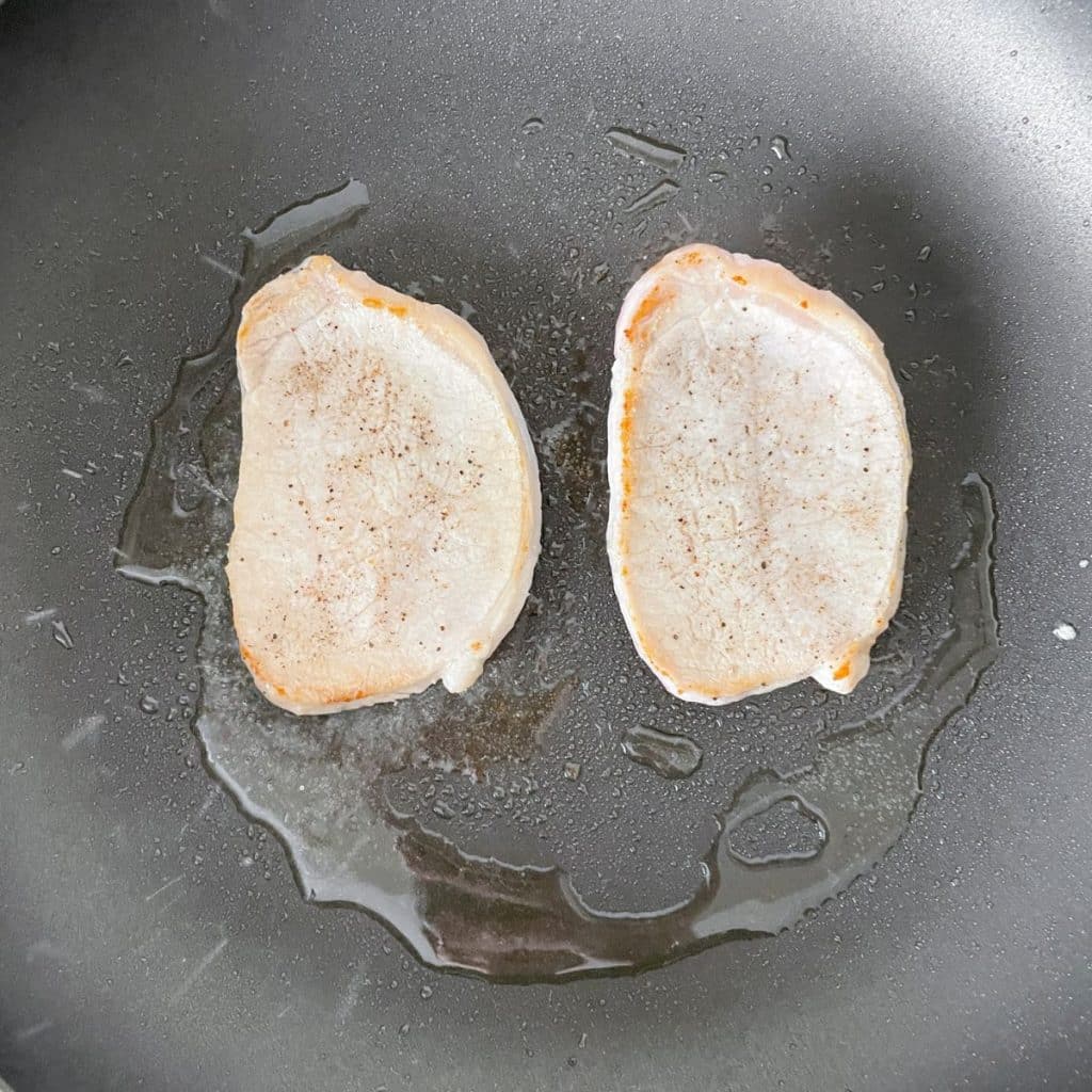 Pork chops in a skillet.