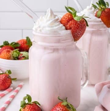 Glass with strawberry milkshake and whipped cream.