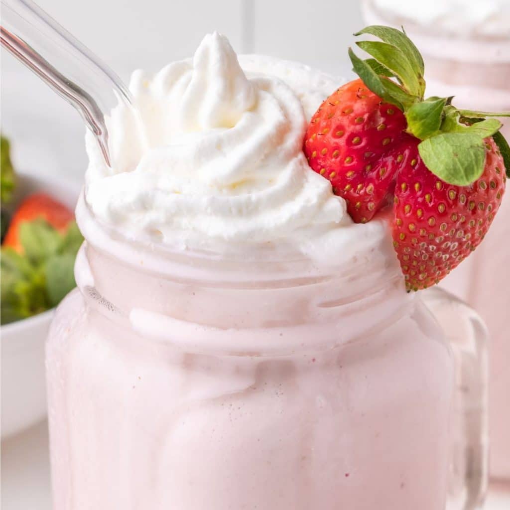 Strawberry milkshake with whipped cream and fresh strawberry.
