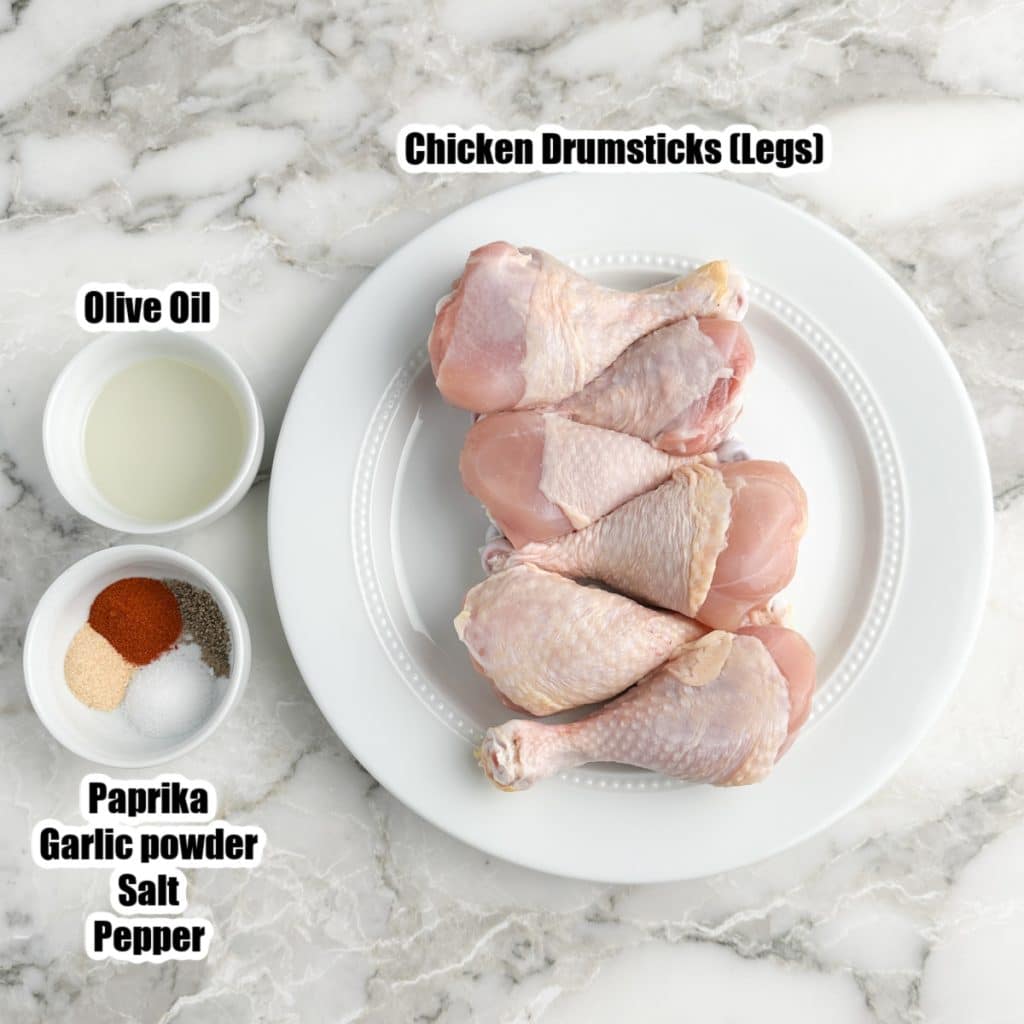 Plate of chicken legs, bowl of oil, bowl of seasonings.