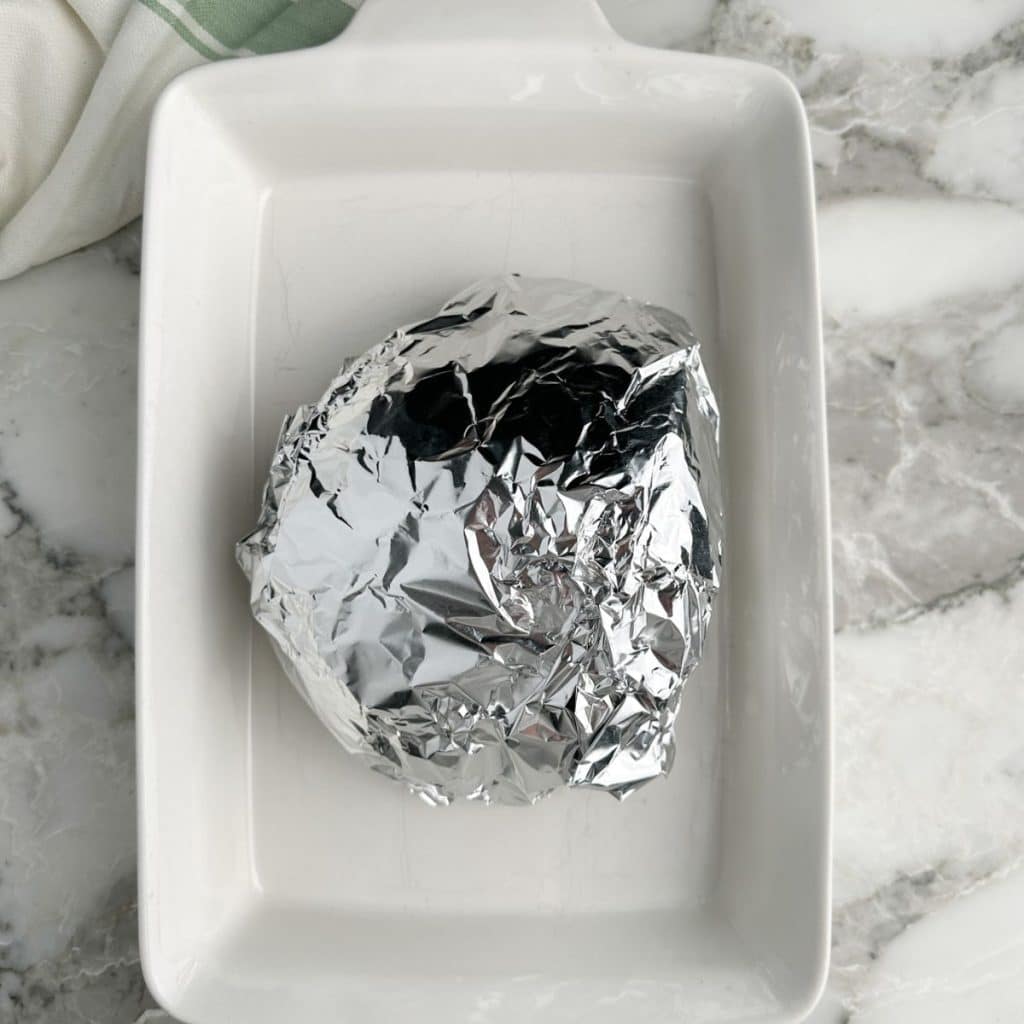 Foil wrapped around ham in a baking dish.