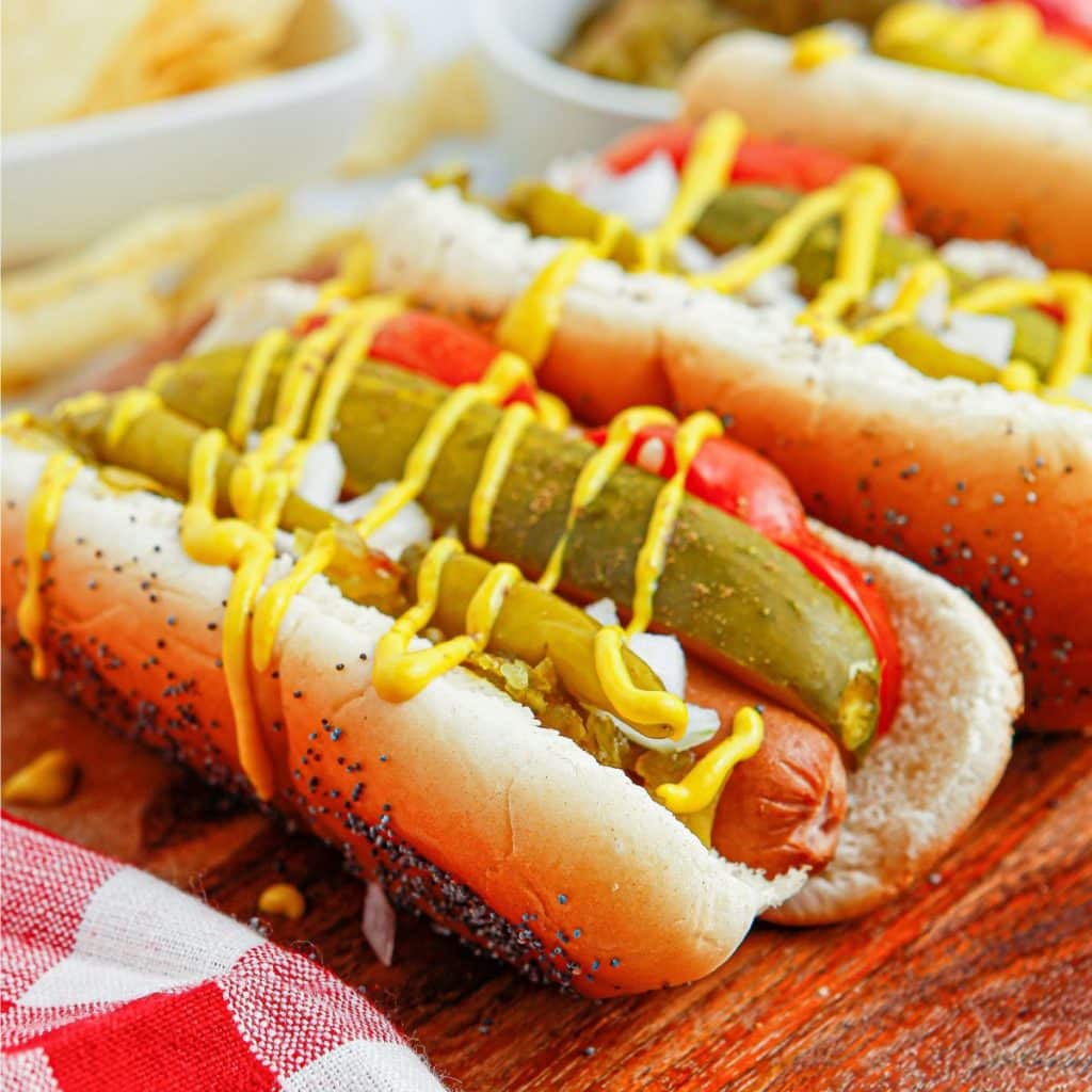 Hot dogs topped with pickles, tomatoes, peppers, and mustard. 