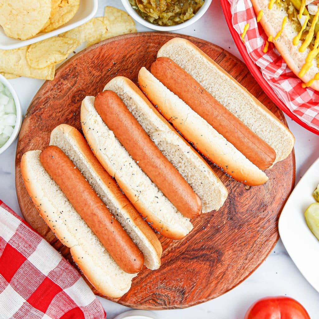 Hot dogs in buns on a wooden plate. 