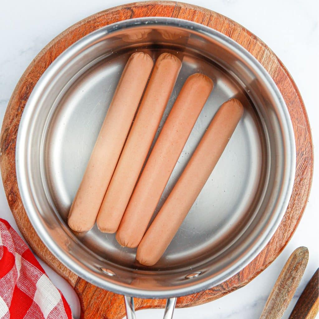 Pot with water and hot dogs. 