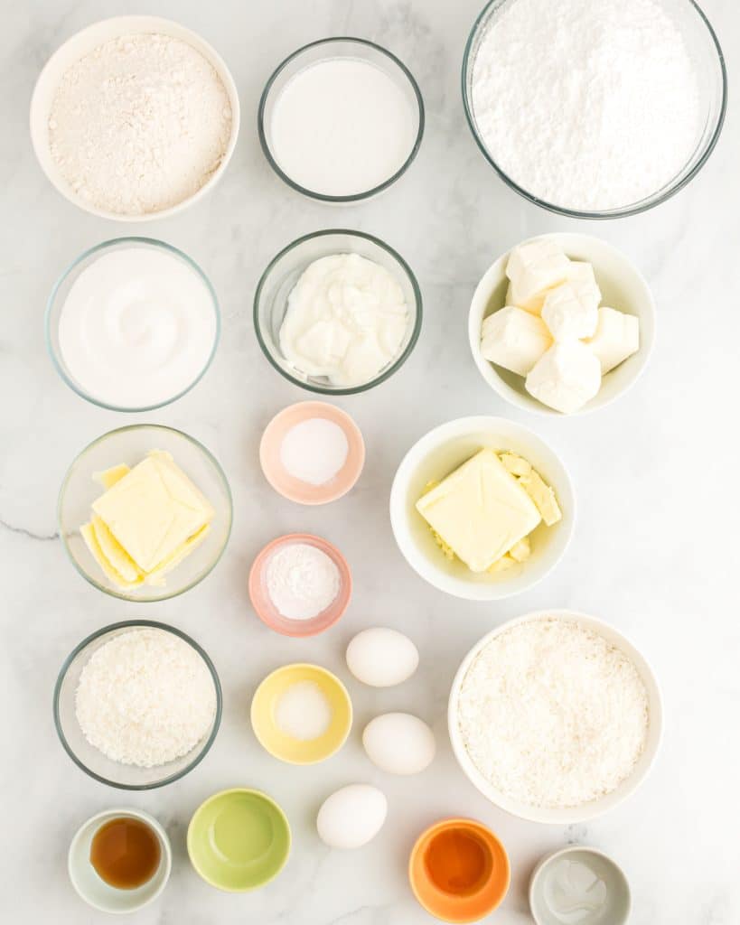 Bowls of flour, sugar, cream cheese, vanilla, butter, and coconut extract.