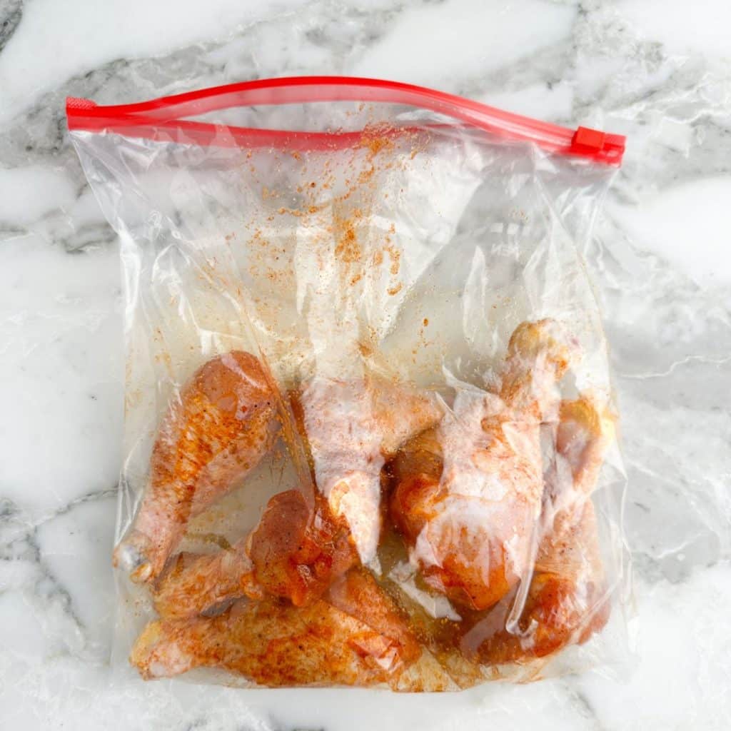 Chicken legs in zip-top bag with seasonings. 