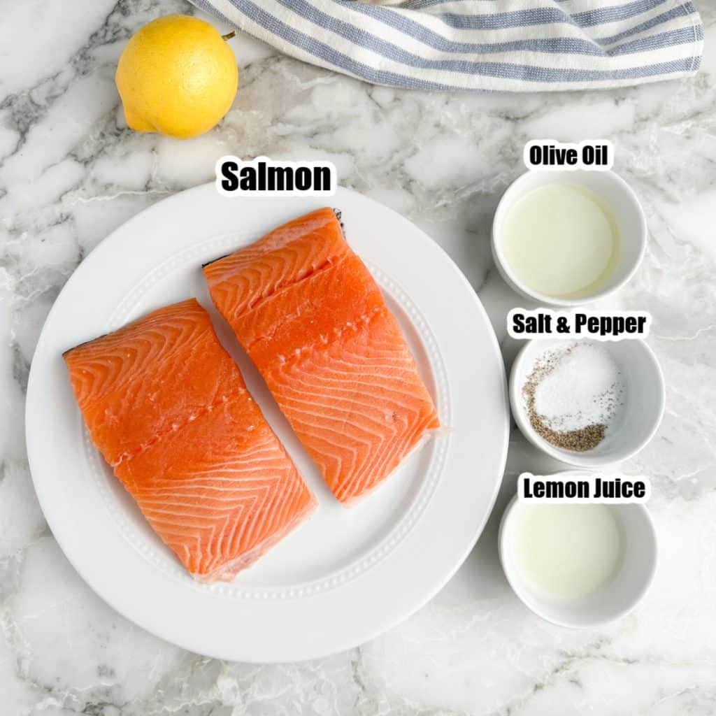 Plate with salmon, bowls with oil, seasonings, and lemon juice. 