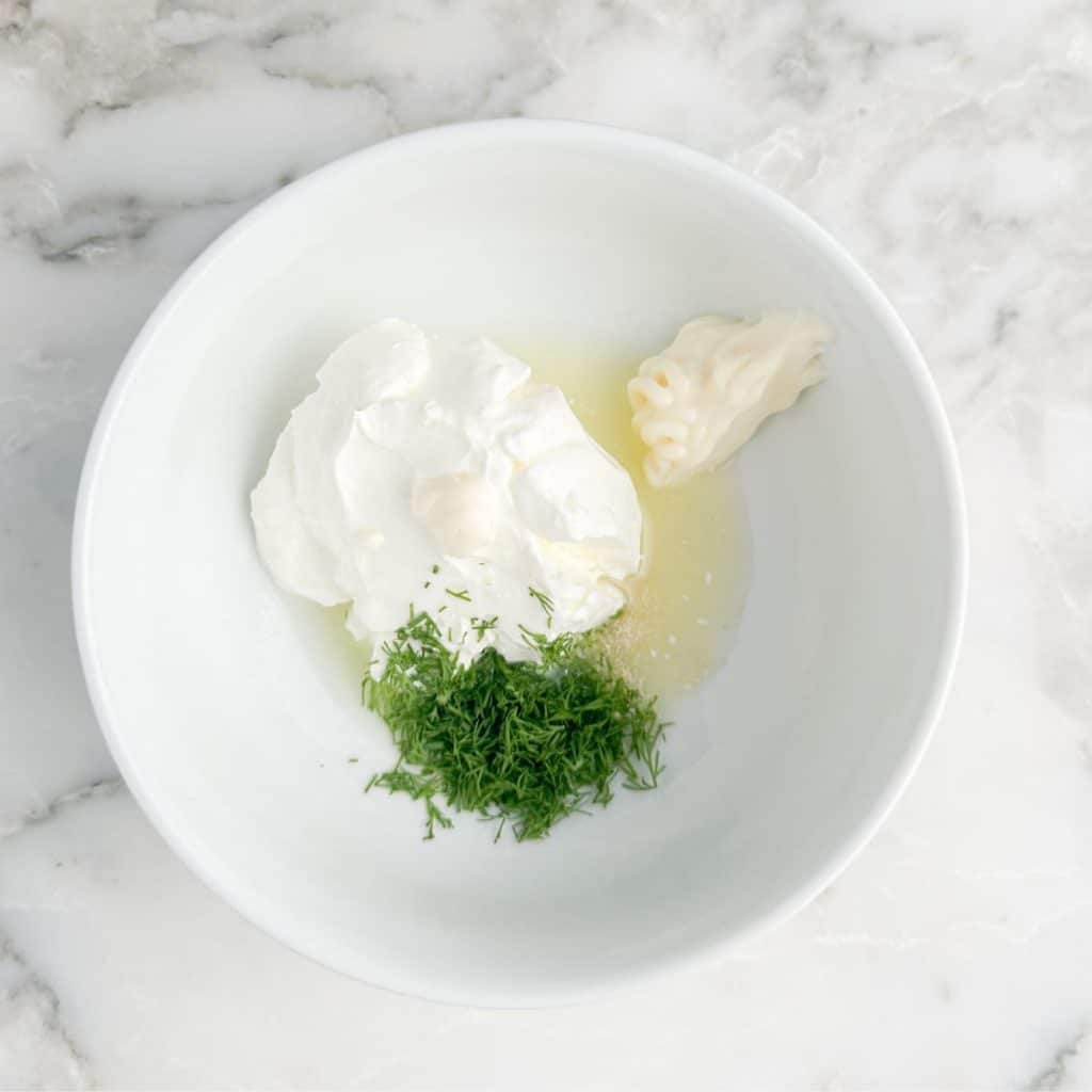 Bowl of sour cream, mayonnaise, dill, and lemon juice.