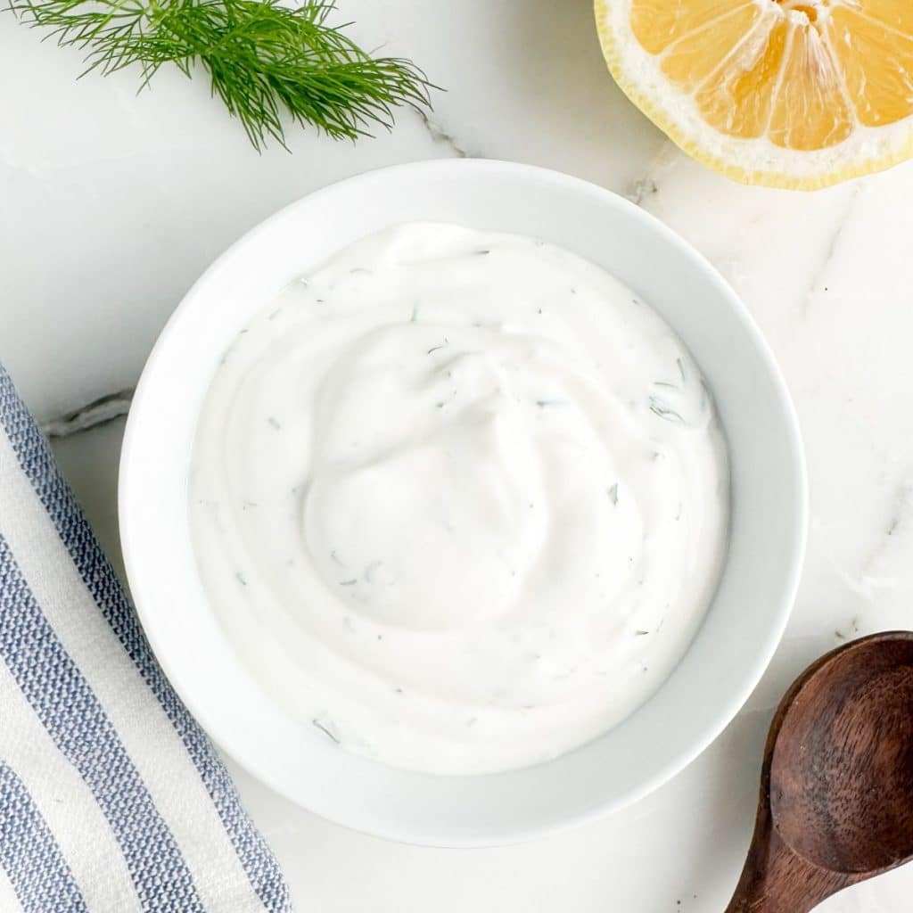 Bowl of dill sauce with a lemon. 