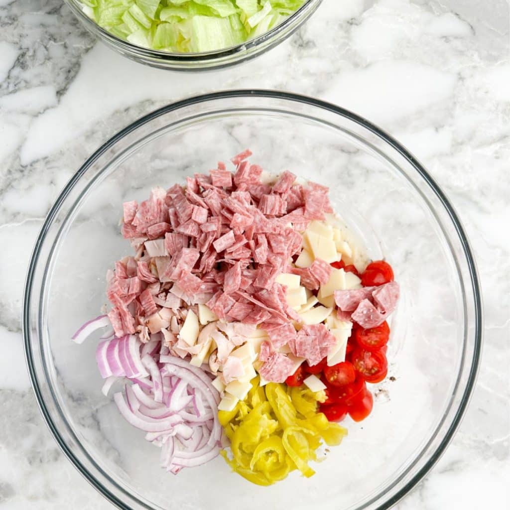 Bowl with chopped lunch meat, onions, tomatoes, cheese, and peppers.