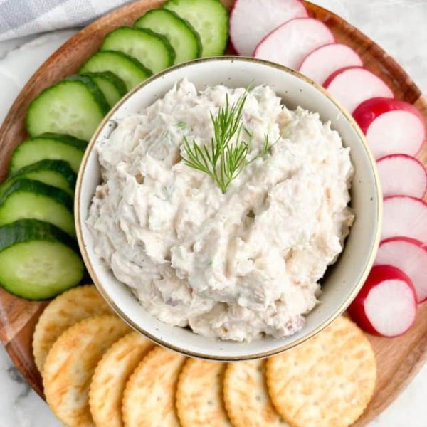 Bowl of salmon dip with cucumbers, radish, and crackers.