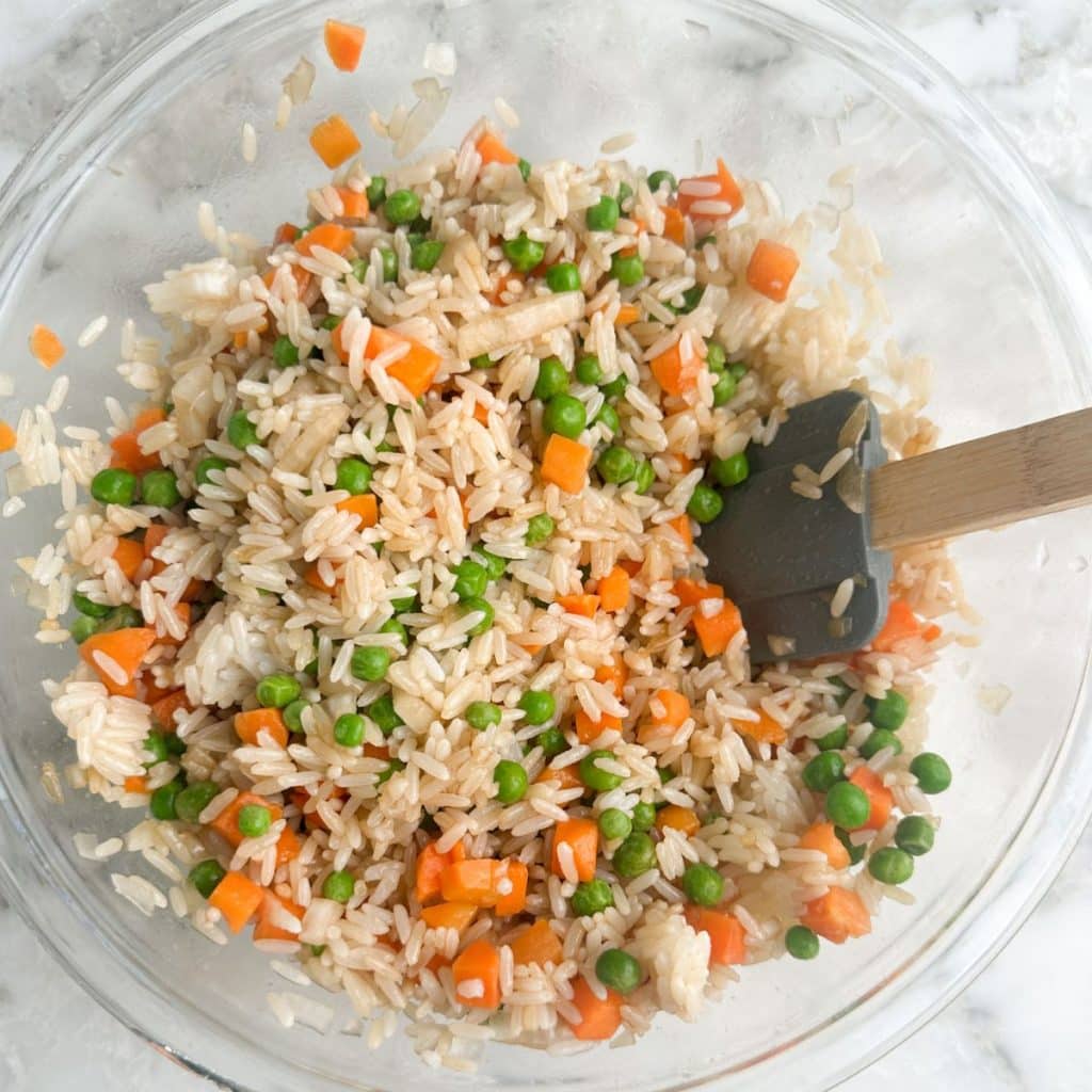 Bowl of rice with carrots and peas.