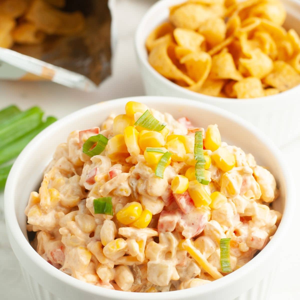 Bowl filled with corn dip and bowl with corn chips.