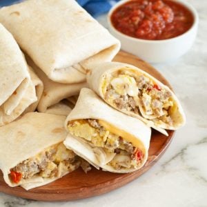 Breakfast burritos on a plate and bowl of salsa.