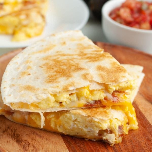 Breakfast quesadilla stacked on wooden plate.