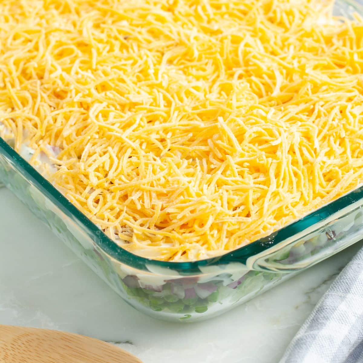 Casserole dish with salad topped with shredded cheese. 