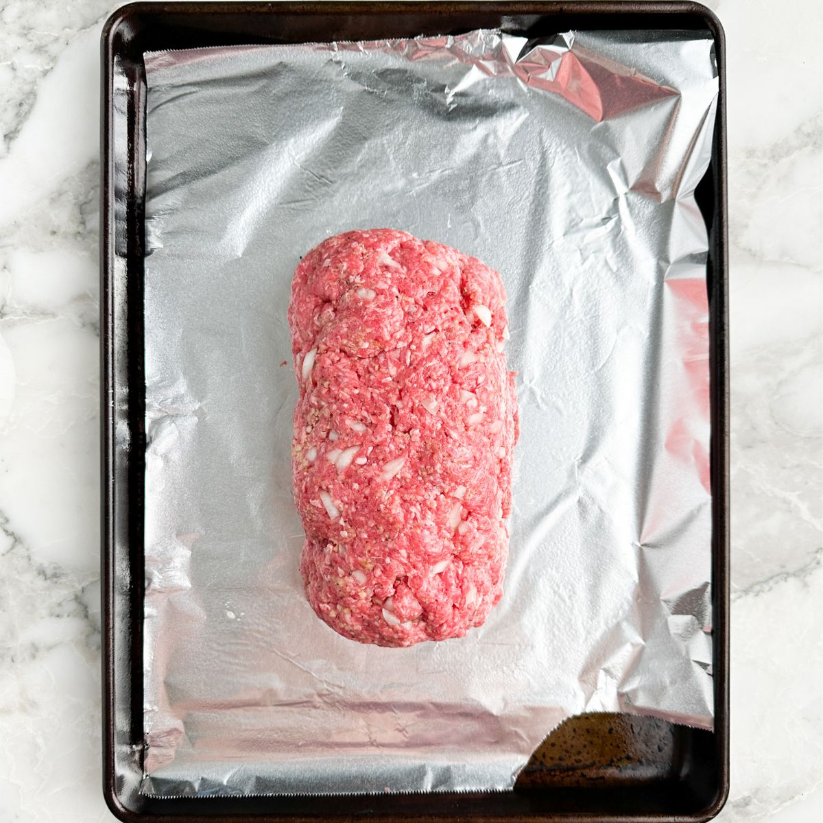 Uncooked meatloaf on a baking pan. 