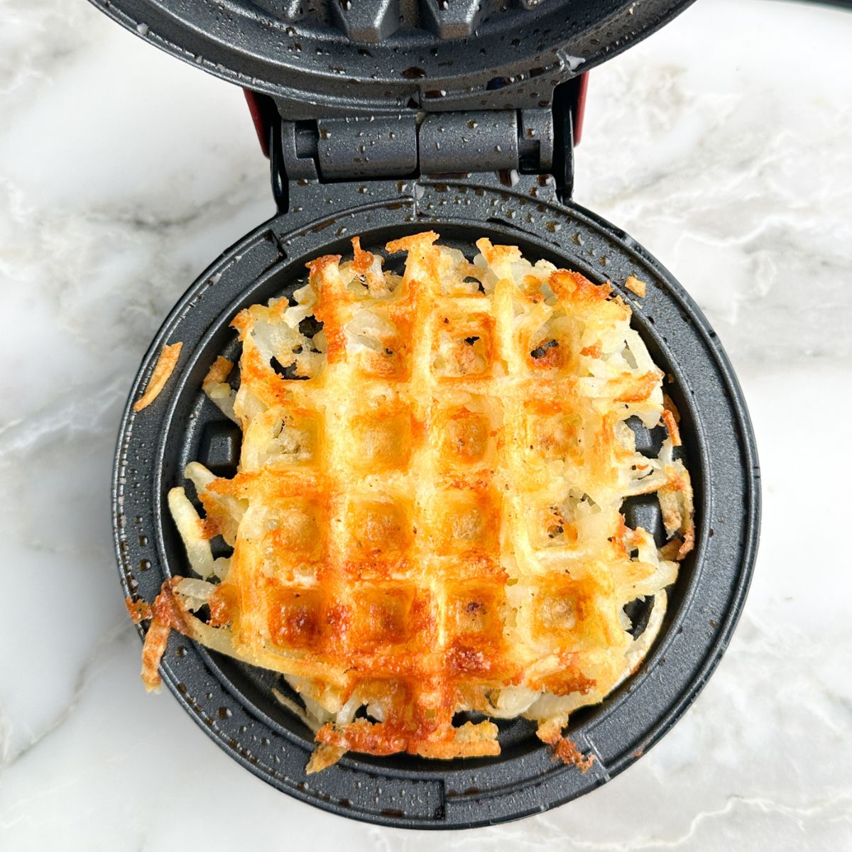 Cooked hash brown waffle in the waffle iron. 