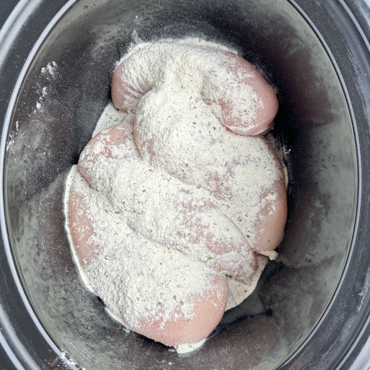 Chicken breast with seasoning in a slow cooker. 