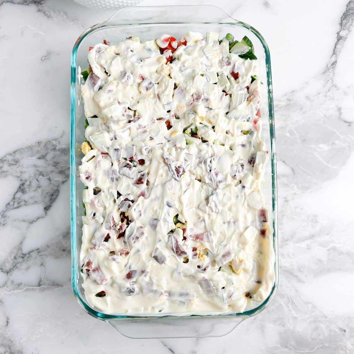Casserole dish with salad and topped with mayonnaise. 