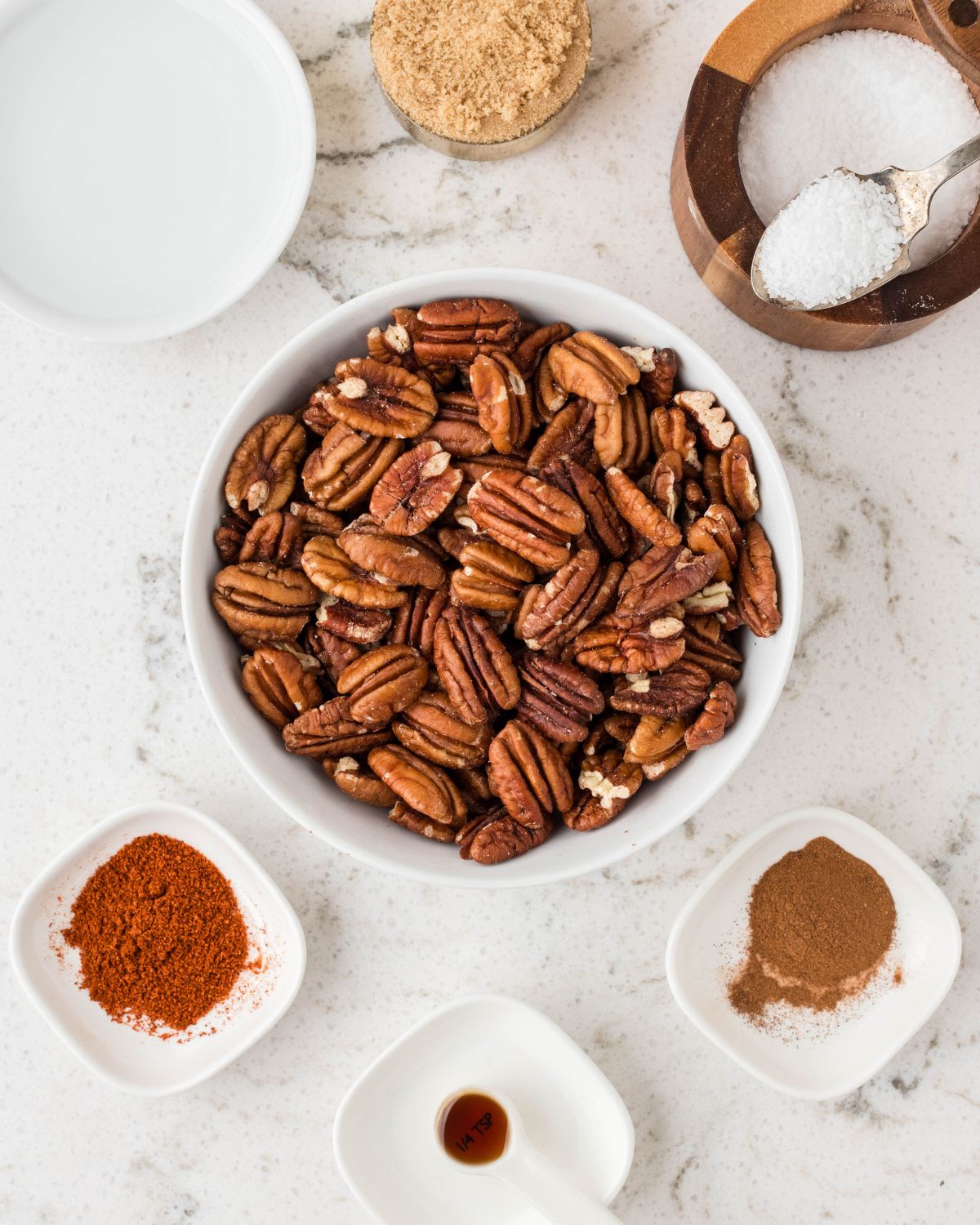 Bowl of pecans, sugar, cinnamon, vanilla, and cayenne. 