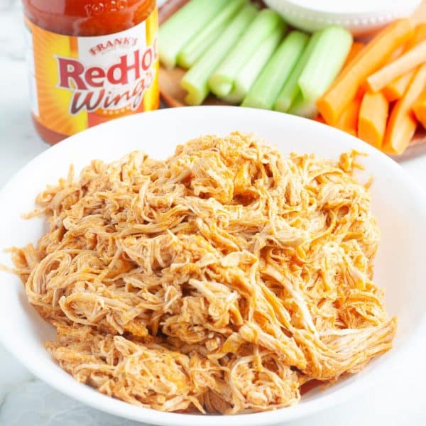 Bowl of shredded chicken with hot sauce.