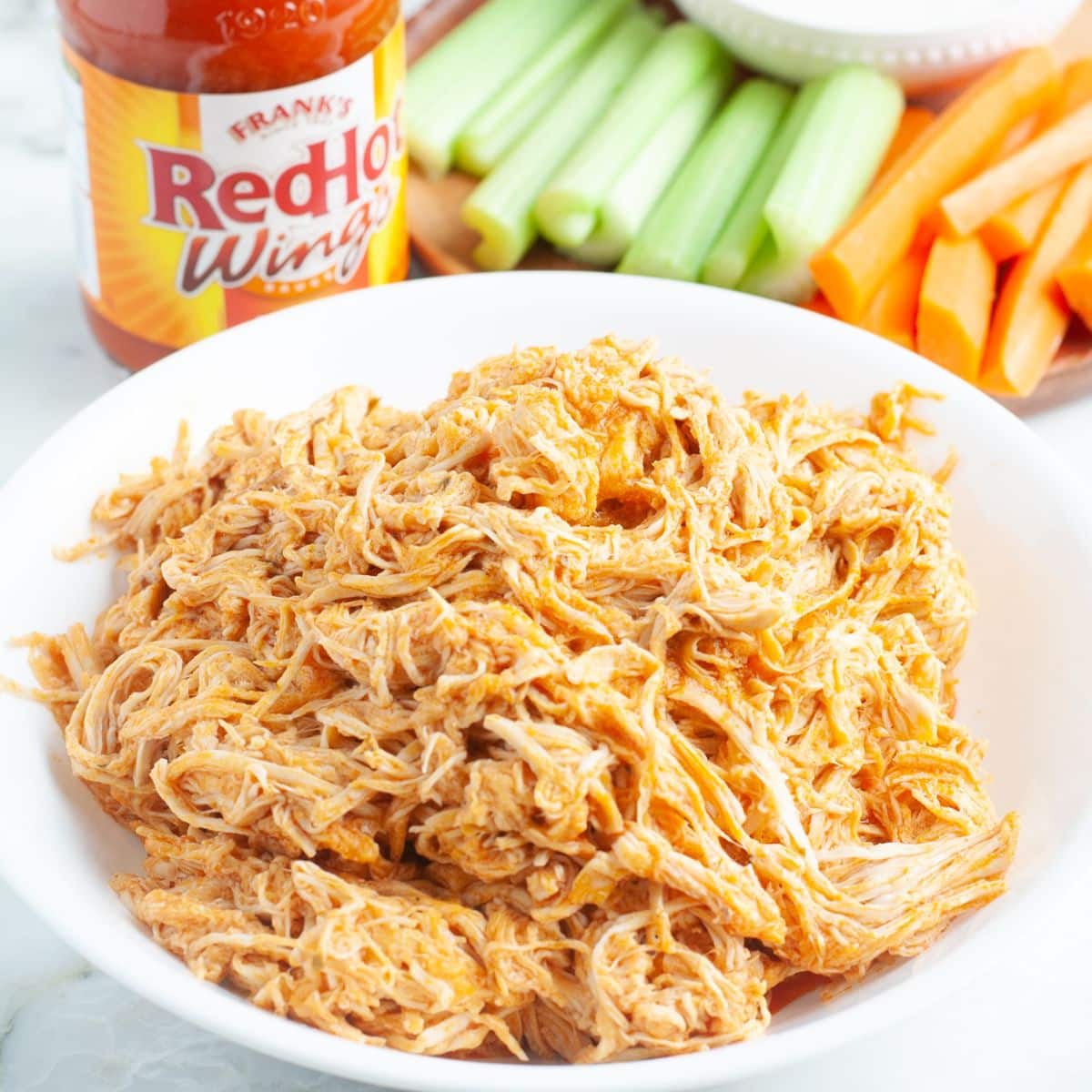 Shredded chicken with buffalo sauce in a bowl. 
