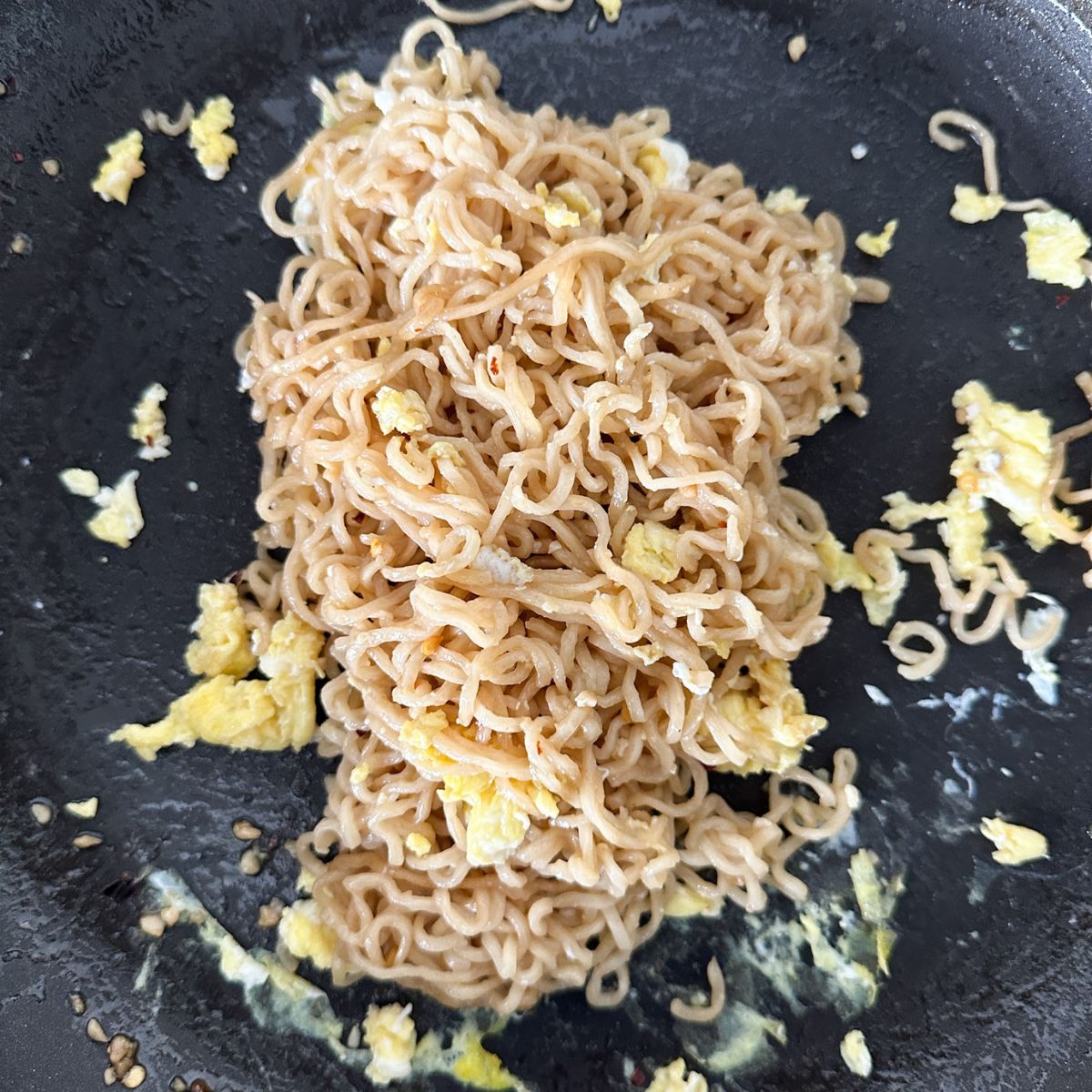 Noodles and scrambled eggs in a pan. 