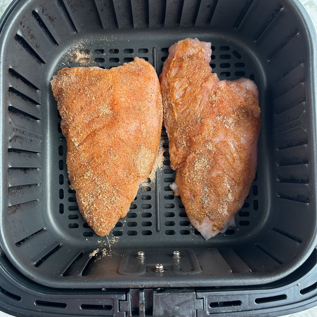 Seasoned turkey tenderloin in air fryer basket. 