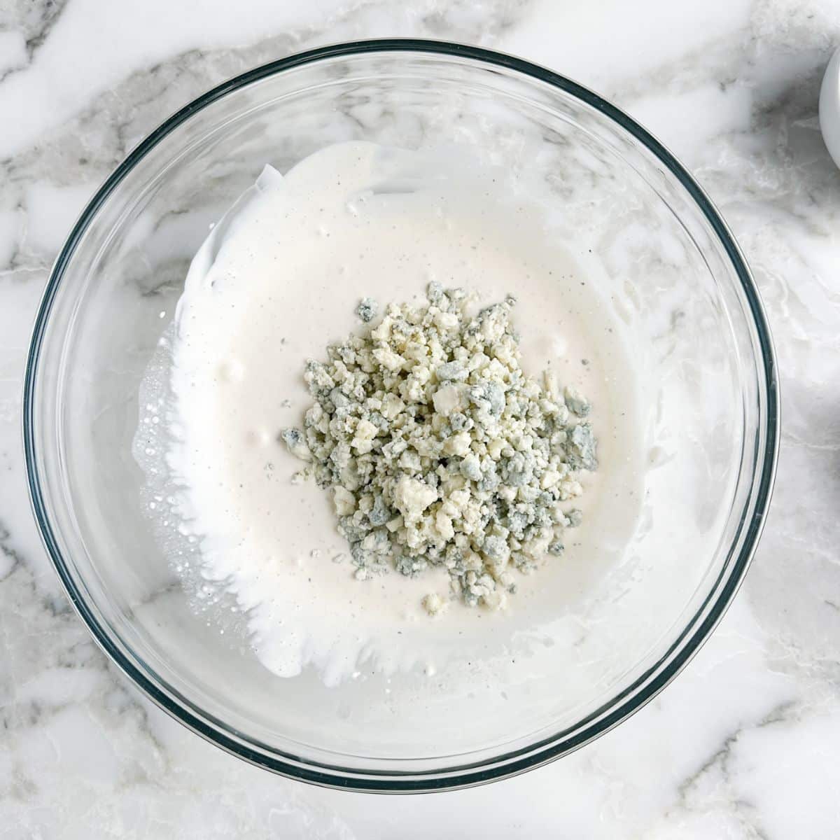 Bowl with mayonnaise dressing and blue cheese crumbles. 