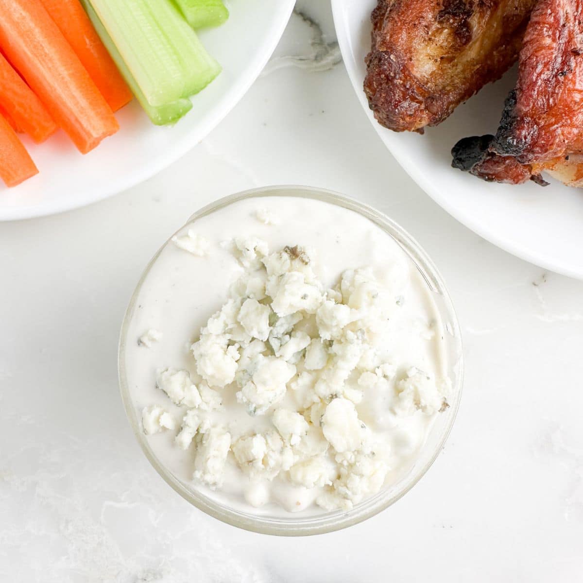 Bowl of blue cheese dressing with chicken wings. 