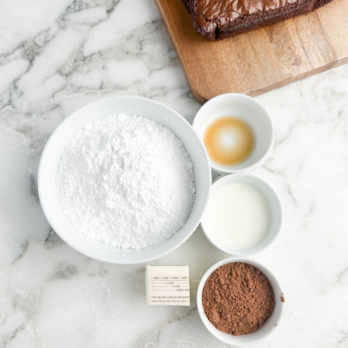 Bowl of powdered sugar, vanilla, milk, cocoa powder, and butter. 